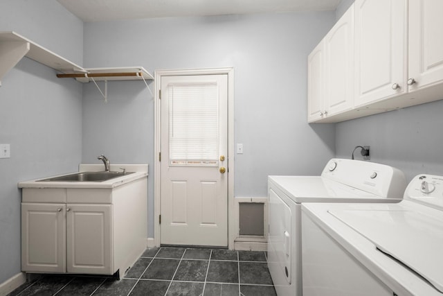 laundry area with a sink, washing machine and clothes dryer, baseboards, cabinet space, and dark tile patterned flooring