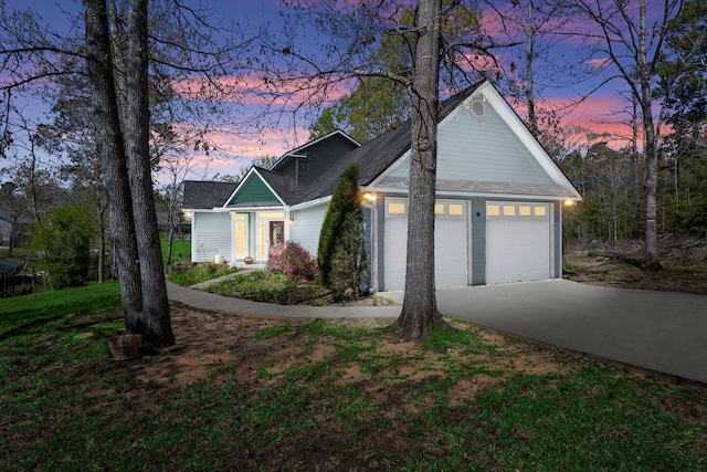 view of front of house with a lawn, driveway, a shingled roof, and an attached garage