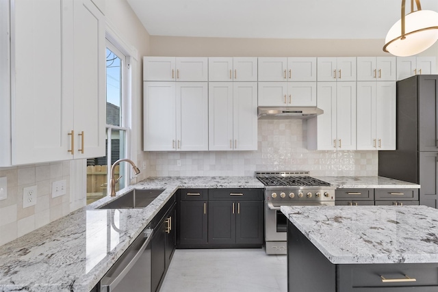 kitchen featuring decorative light fixtures, appliances with stainless steel finishes, white cabinetry, a sink, and under cabinet range hood