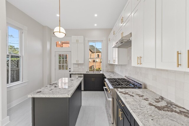 kitchen with light stone counters, stainless steel appliances, pendant lighting, white cabinets, and a kitchen island