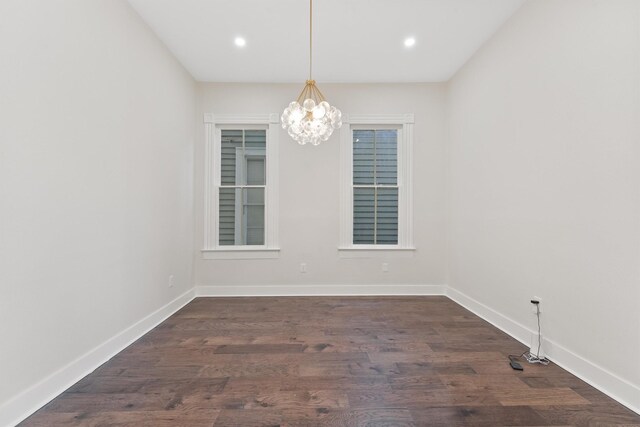 unfurnished room featuring dark hardwood / wood-style flooring and a notable chandelier