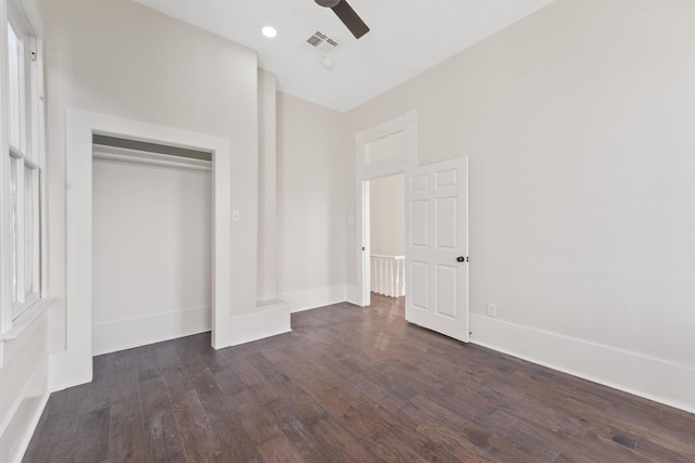 unfurnished bedroom with dark wood-style floors, a closet, visible vents, ceiling fan, and baseboards