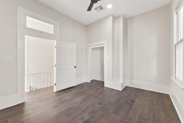 spare room featuring a wealth of natural light, a ceiling fan, visible vents, and dark wood-style flooring