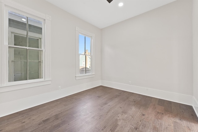 spare room with dark wood-style floors, baseboards, and a ceiling fan