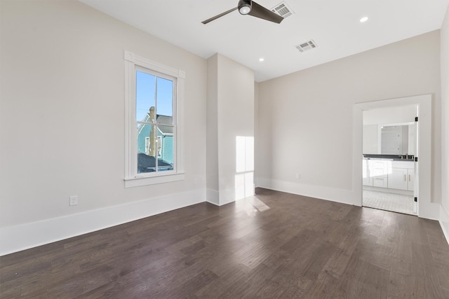 empty room featuring ceiling fan, dark wood-style flooring, visible vents, and baseboards