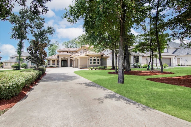 mediterranean / spanish house featuring a garage and a front lawn