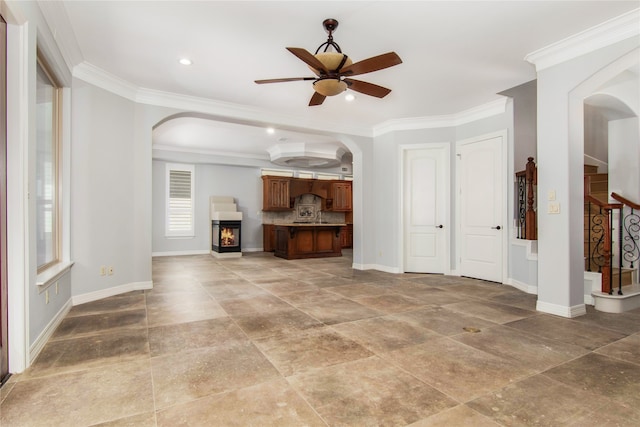 unfurnished living room featuring ceiling fan and ornamental molding