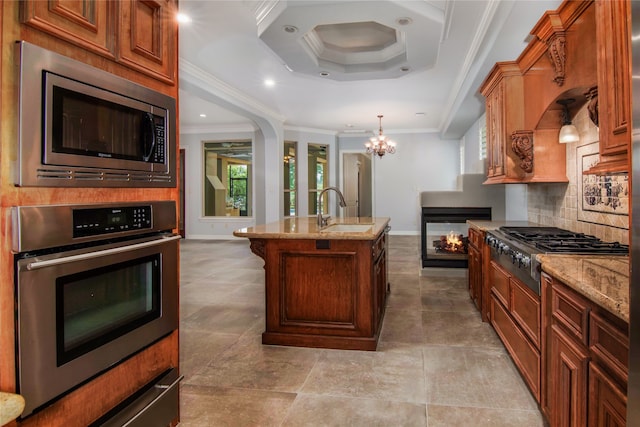 kitchen featuring stainless steel appliances, a kitchen island with sink, crown molding, and sink