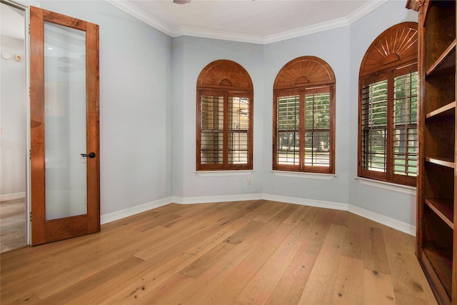 empty room with light wood-type flooring, crown molding, and french doors