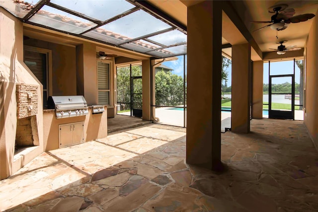 view of patio featuring area for grilling, ceiling fan, exterior kitchen, and glass enclosure