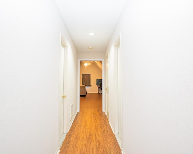 hallway featuring light wood-type flooring, baseboards, and visible vents