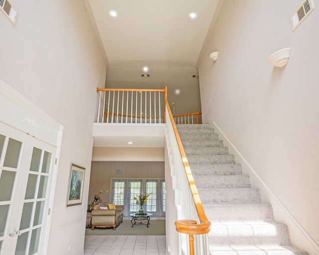 staircase featuring a high ceiling, french doors, and tile patterned floors