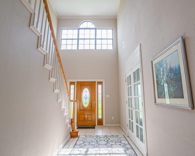 tiled foyer with baseboards, stairway, and crown molding