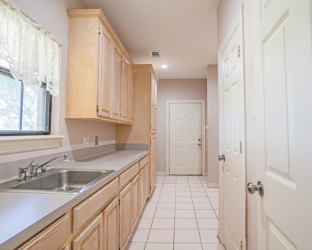 kitchen with light countertops, a sink, light brown cabinetry, light tile patterned floors, and visible vents