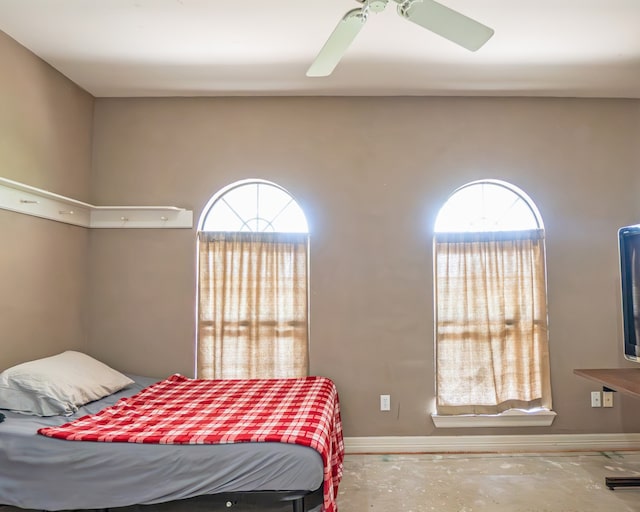 bedroom featuring concrete flooring, multiple windows, and ceiling fan