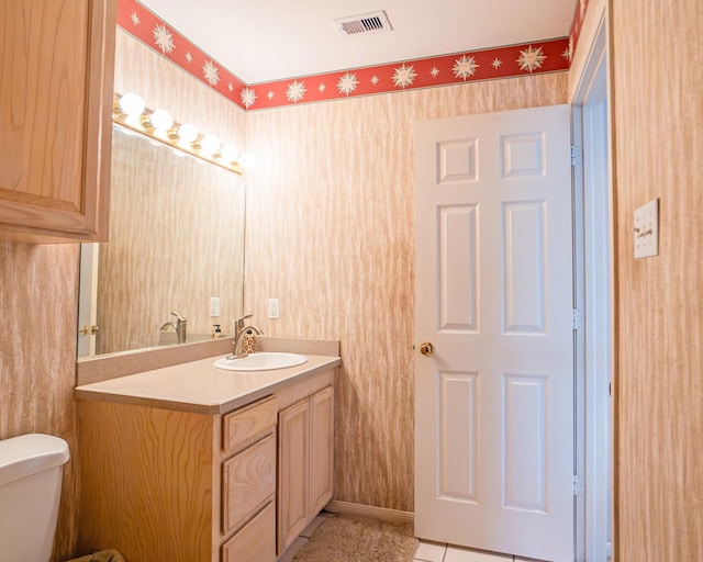 half bath with vanity, toilet, baseboards, wallpapered walls, and visible vents