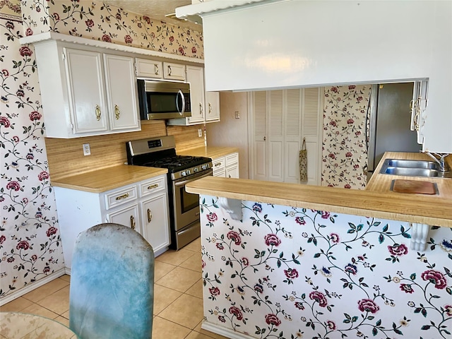 kitchen with light tile patterned flooring, sink, stainless steel appliances, and backsplash