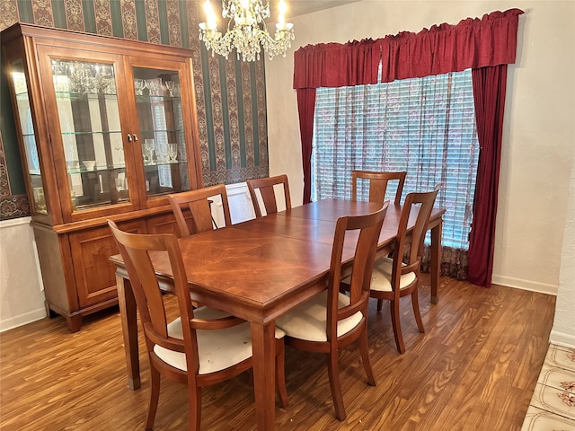 dining area with hardwood / wood-style floors and an inviting chandelier