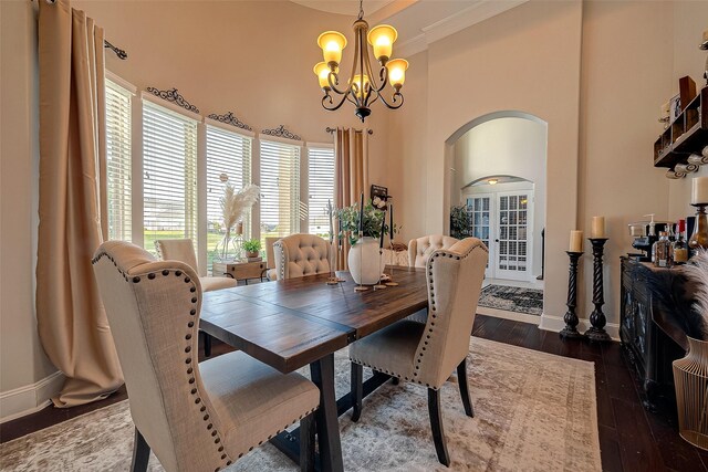 dining space featuring dark wood-type flooring, plenty of natural light, a chandelier, and a high ceiling