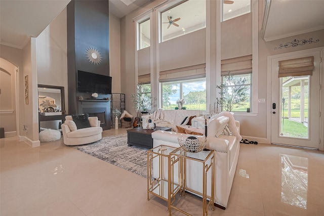 living room with crown molding, plenty of natural light, ceiling fan, and a towering ceiling