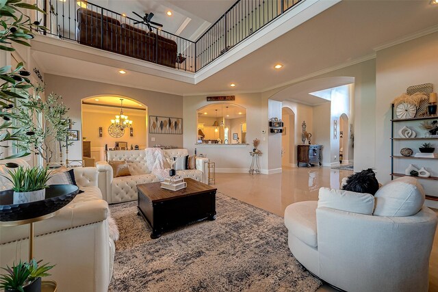 living room featuring ornamental molding, a towering ceiling, and a chandelier