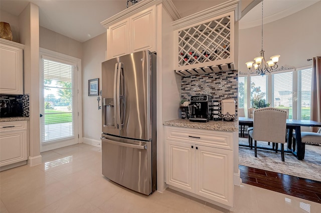 kitchen featuring white cabinetry, stainless steel fridge with ice dispenser, tasteful backsplash, and pendant lighting