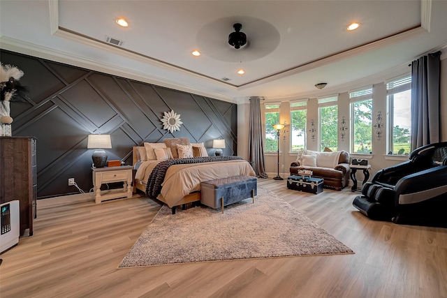 bedroom featuring ornamental molding, light hardwood / wood-style flooring, and a tray ceiling