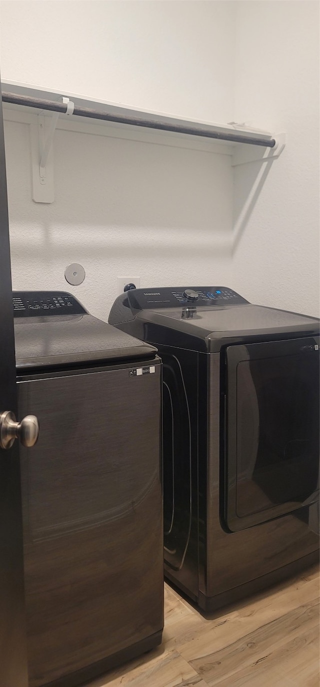 laundry room featuring washer and clothes dryer and light wood-type flooring