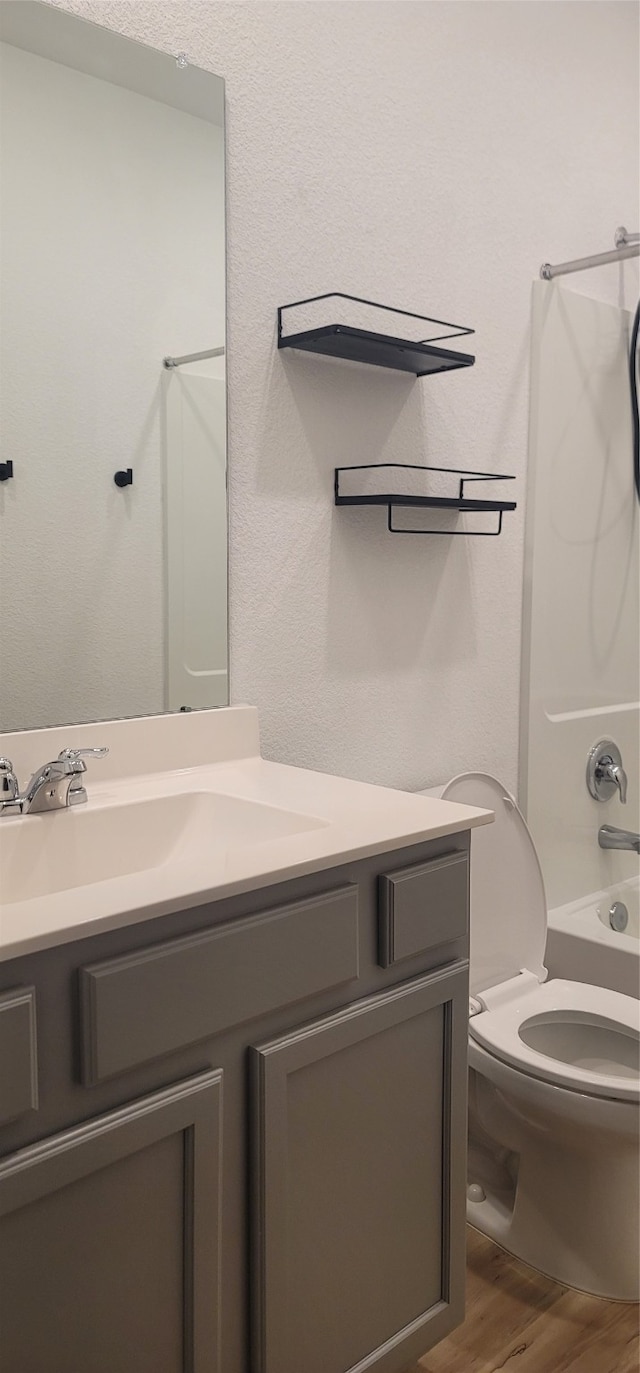 full bathroom featuring hardwood / wood-style flooring, toilet, shower / washtub combination, and vanity