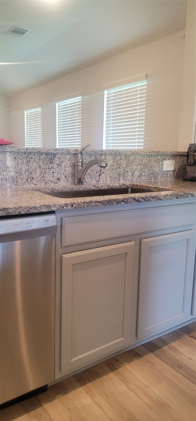 kitchen featuring stone counters, light hardwood / wood-style flooring, sink, and stainless steel dishwasher