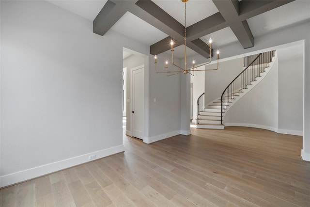 unfurnished living room featuring light wood-type flooring, beamed ceiling, coffered ceiling, and a notable chandelier