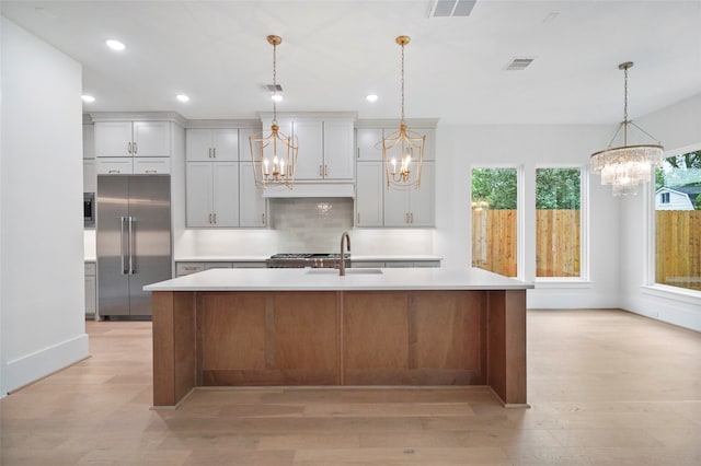 kitchen featuring pendant lighting, a large island with sink, stainless steel built in fridge, and sink