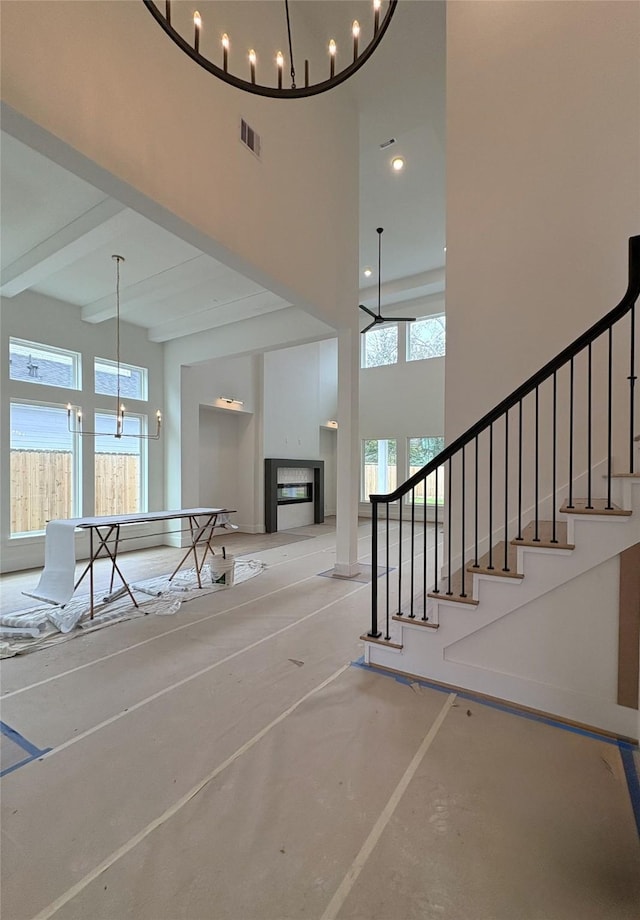 interior space with beamed ceiling, a high ceiling, a chandelier, and concrete flooring