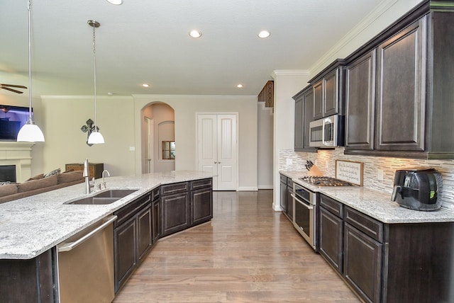 kitchen with decorative light fixtures, dark brown cabinets, sink, and appliances with stainless steel finishes