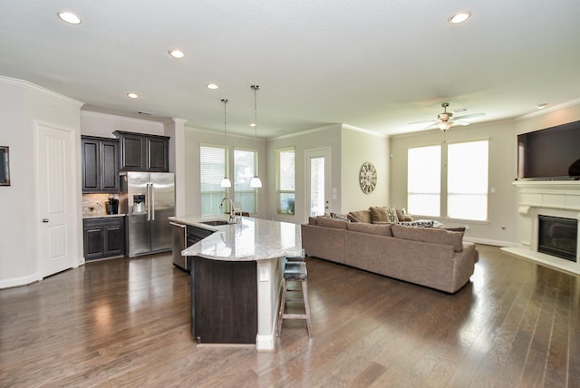 kitchen with a center island with sink, sink, decorative light fixtures, a kitchen bar, and stainless steel appliances