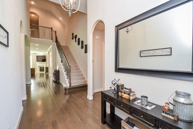 hallway with a notable chandelier, dark hardwood / wood-style floors, and a high ceiling