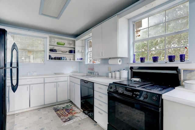 kitchen with white cabinets, black appliances, sink, and light tile patterned floors