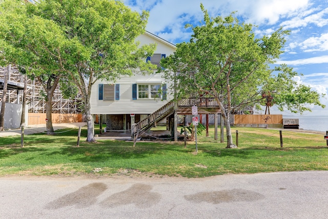 view of property hidden behind natural elements with a water view and a front lawn