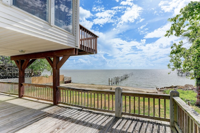 wooden terrace featuring a water view and a lawn