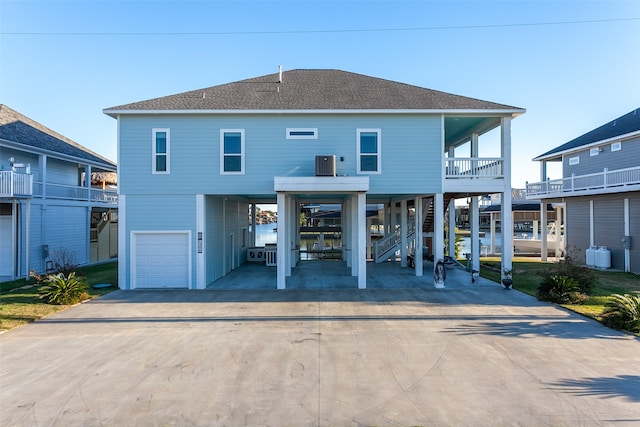 1295 Lagoon Dr, Crystal Beach, TX 77650 - rear view of house featuring a carport, concrete driveway, a garage, and stairway