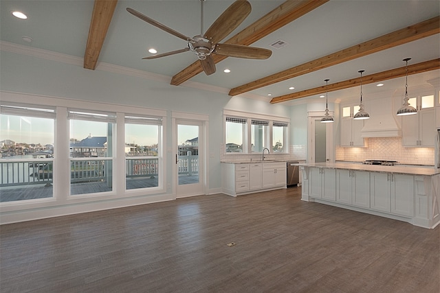 unfurnished living room with crown molding, beamed ceiling, dark hardwood / wood-style flooring, and a wealth of natural light