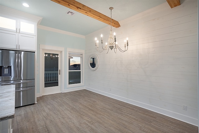 unfurnished dining area with a notable chandelier, beam ceiling, and hardwood / wood-style floors