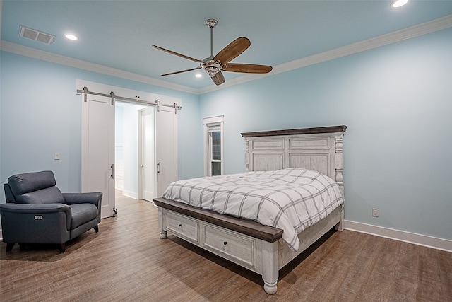 bedroom with ornamental molding, ceiling fan, wood-type flooring, and a barn door