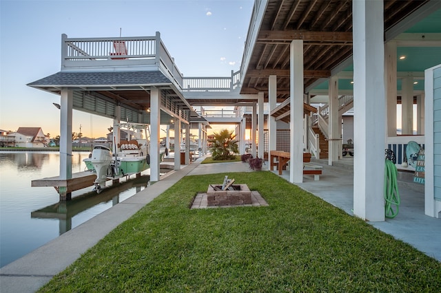 dock area with a water view, a yard, a patio area, and an outdoor fire pit