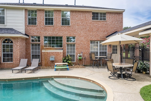 rear view of house featuring a fenced in pool and a patio