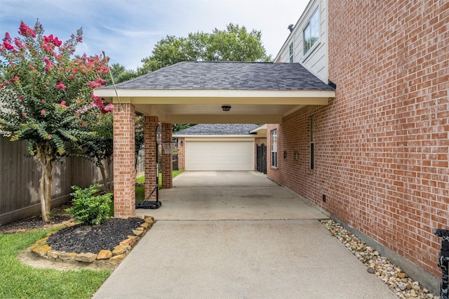 view of patio / terrace with a carport, a garage, and an outbuilding