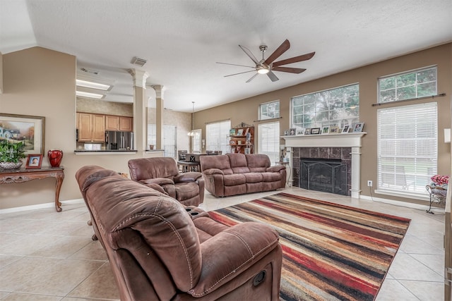 living room with a tile fireplace, ceiling fan, a healthy amount of sunlight, and light tile patterned flooring