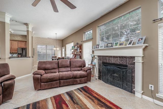 living room with a fireplace, light tile patterned floors, a textured ceiling, and ceiling fan