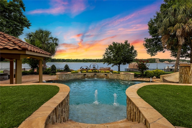 pool at dusk featuring a yard, a gazebo, and a water view