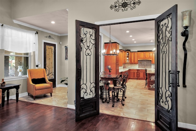 foyer entrance with light wood-style flooring, recessed lighting, crown molding, baseboards, and an inviting chandelier